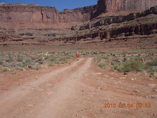 93 774. Canyonlands Lathrop Trail hike - Adam running on white rim road - back