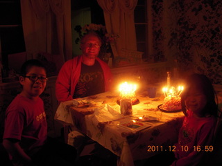 Gaby and Adam and two lit-candle cakes and Cecelia